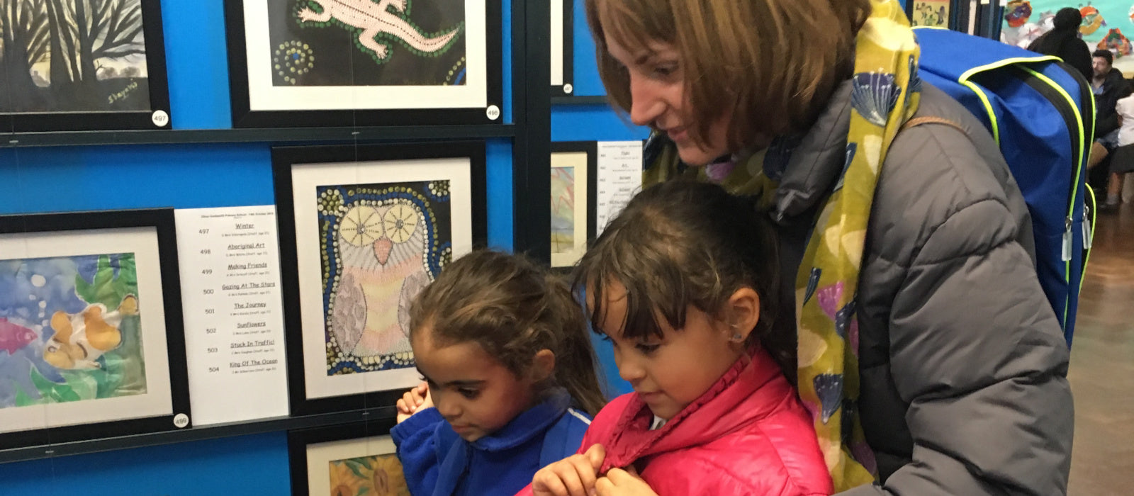 Parents and children admiring the professionally framed artwork at a school exhibition